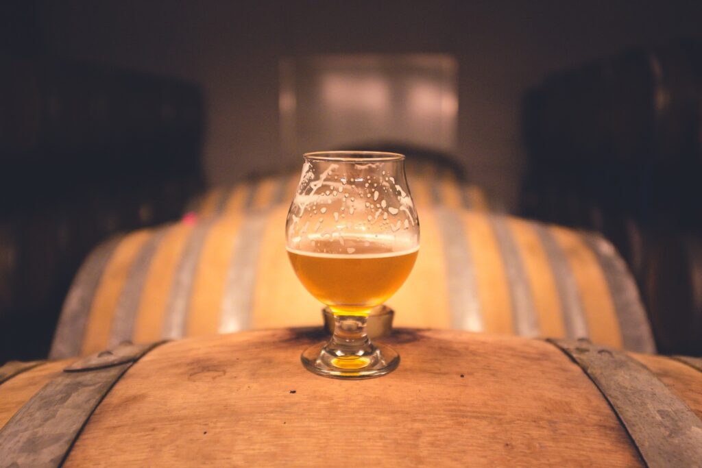 close up of beer cup on wooden barrel 