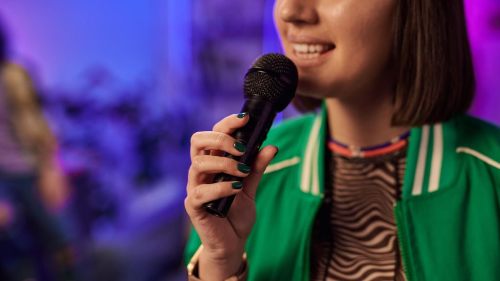 woman in green jacket performing karaoke song