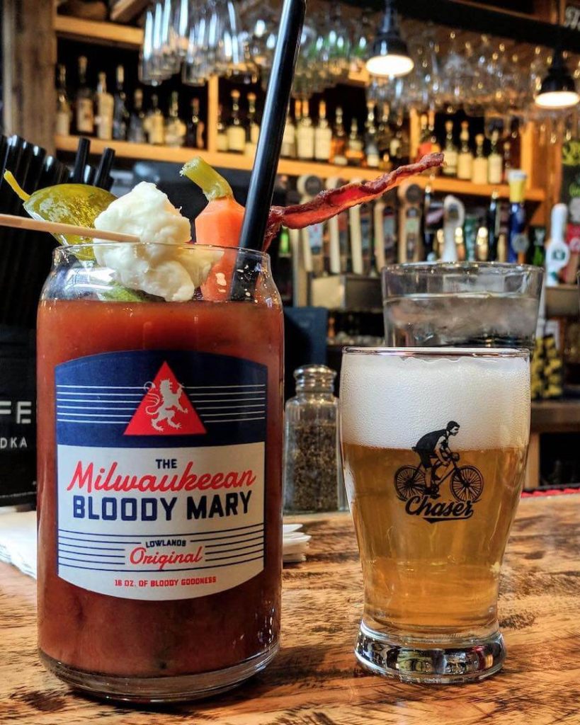 A Bloody Mary cocktail and a beer on a bar counter.